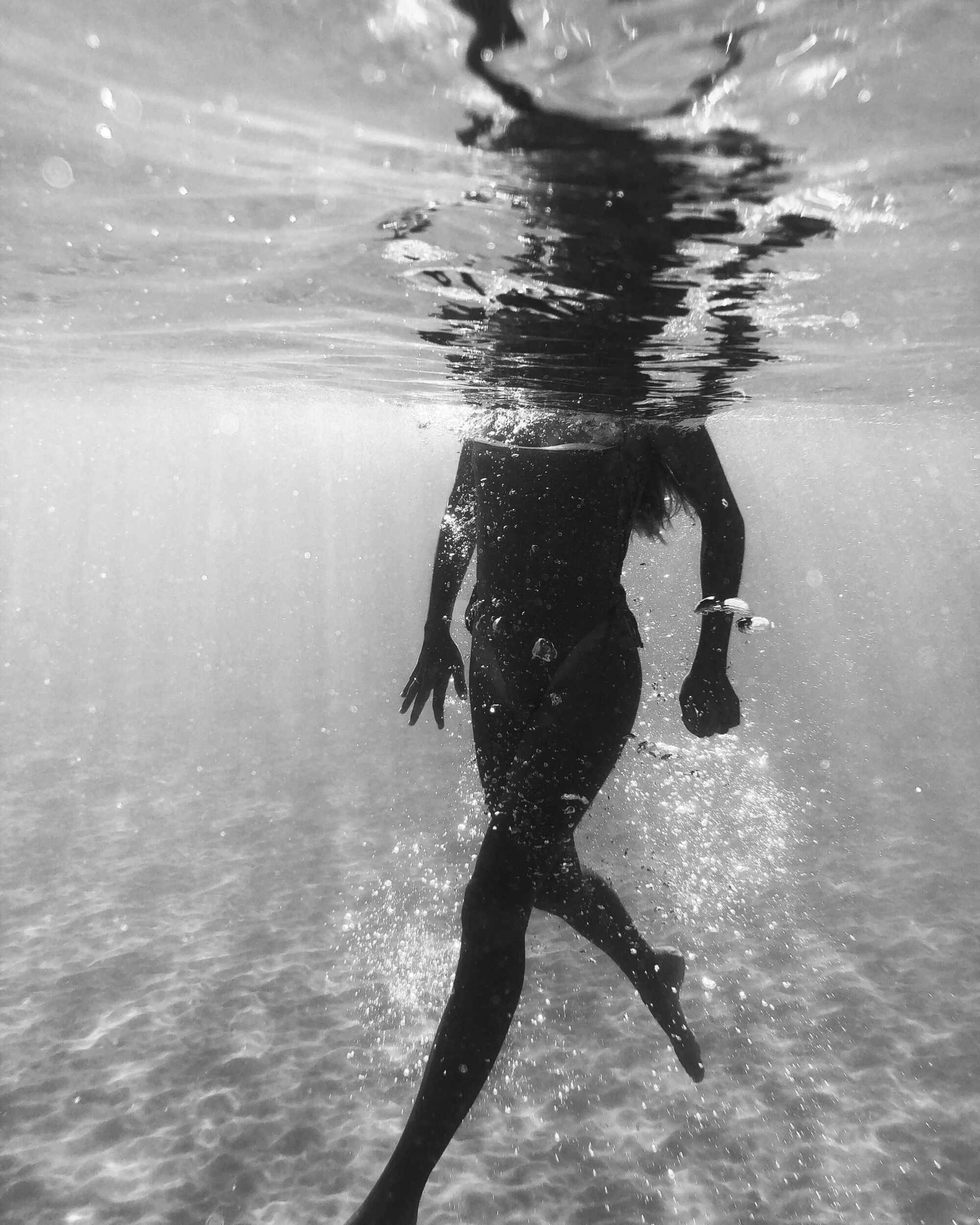 black and white photo of woman swimming in the ocean